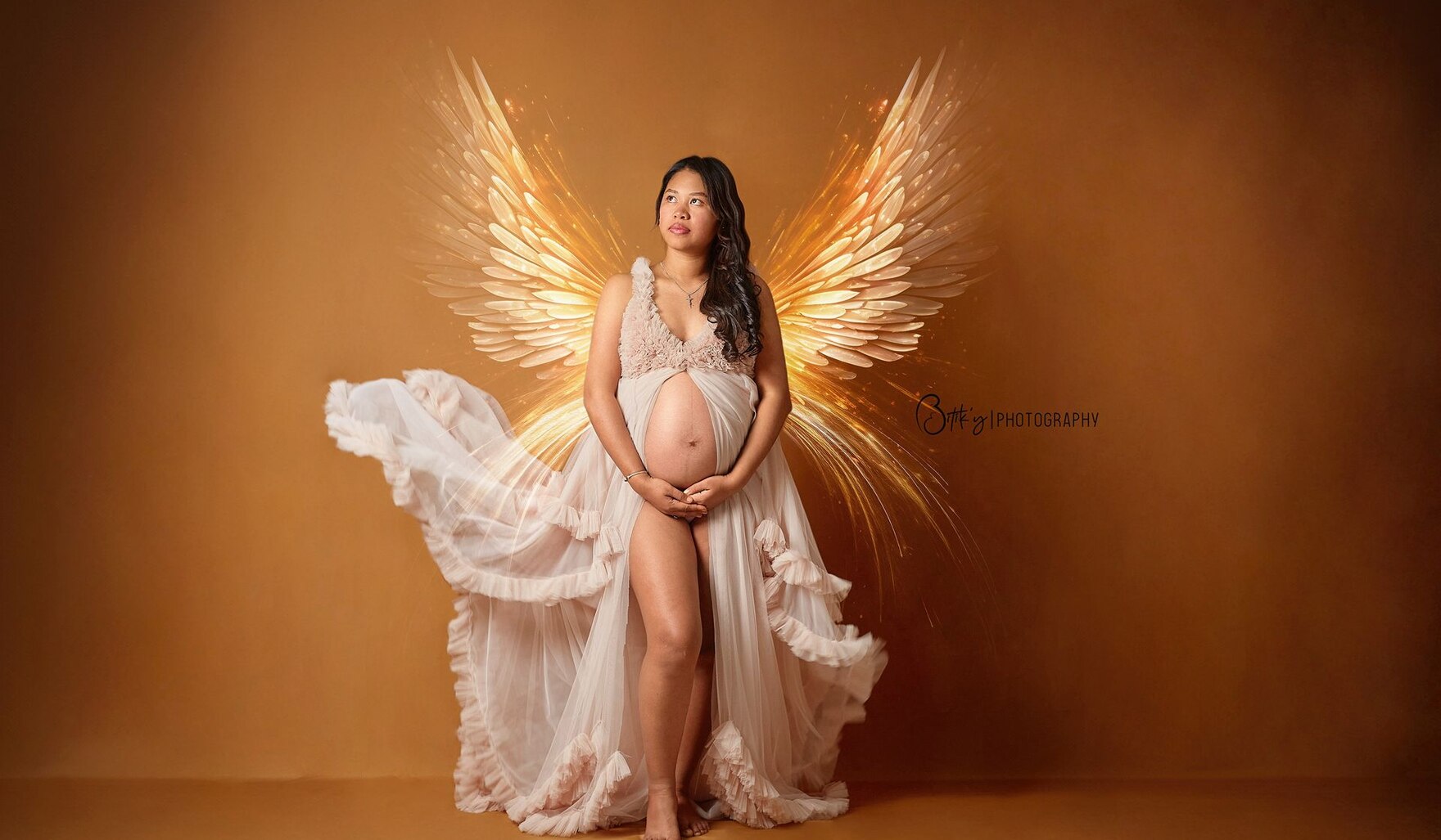 Une femme enceinte en robe claire, des ailes de lumière derrière elle, sur fond chaud.